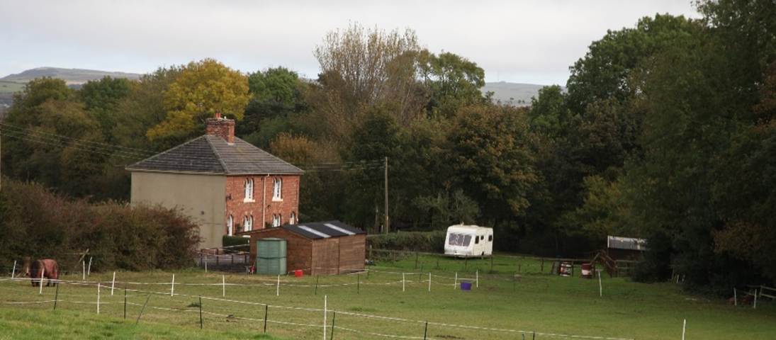 A house and camper in a field
Description automatically generated
